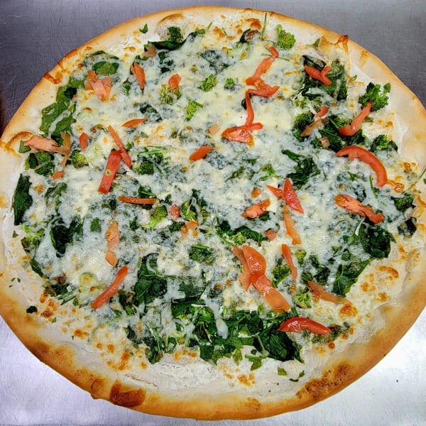 Cedar's Pizza white pizza with melted cheese, spinach, broccoli, and sliced tomatoes.